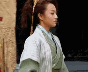 a woman in a traditional costume is standing in front of a black wall .