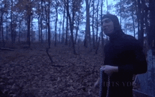 a man in a black robe is standing in the woods