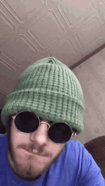 a man with a beard wearing a green hat and sunglasses