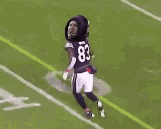 two football players are fighting on the field and one of them has a mask on his head .