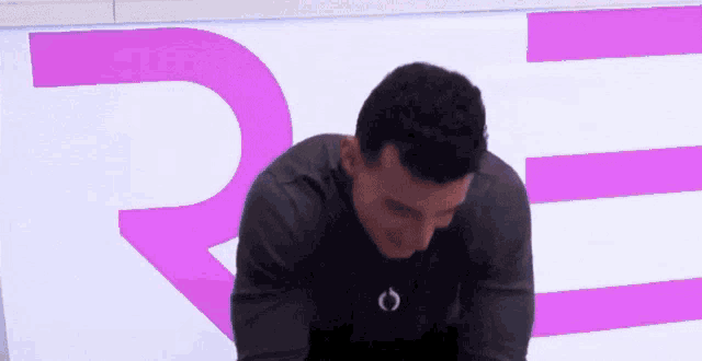 a man is sitting in front of a sign that says r.