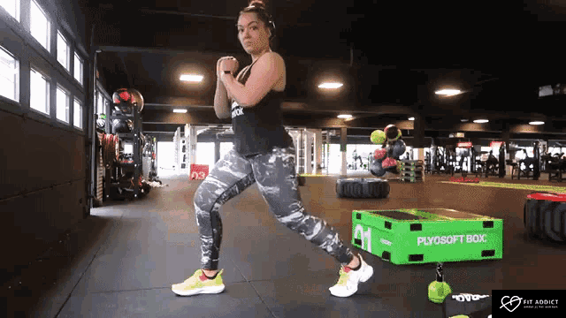 a woman is doing exercises in a gym with a green box that says plyosoft box