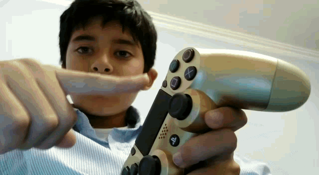 a boy is holding a playstation controller in his hands