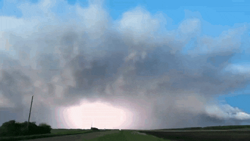 a lightning strike is visible in the sky above a field