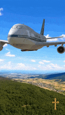 a large airplane flying over a lush green hillside