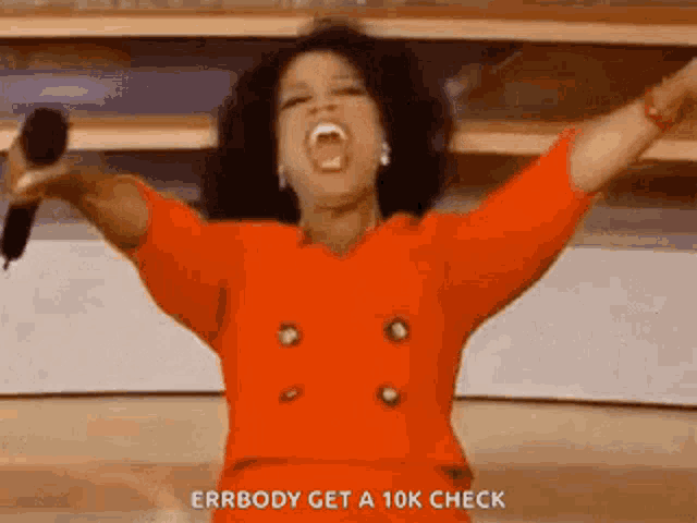 oprah winfrey is singing into a microphone with her arms outstretched .