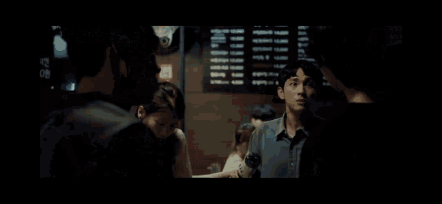 a group of people standing around a table in a dark room with a menu behind them