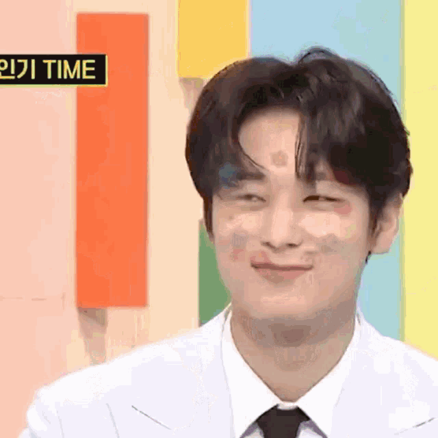 a man in a white suit and tie is smiling in front of a colorful background .