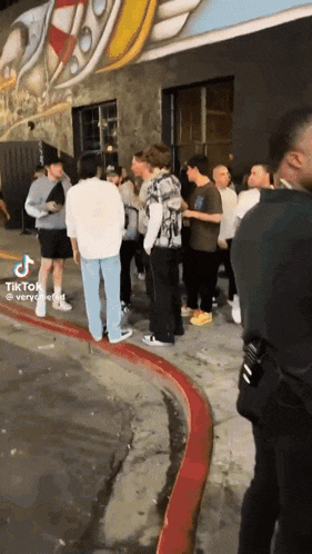 a group of people are standing on a sidewalk outside of a building .