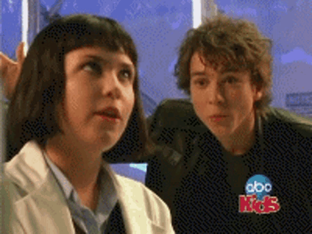 a boy and a girl are sitting next to each other in front of a abc kids sign