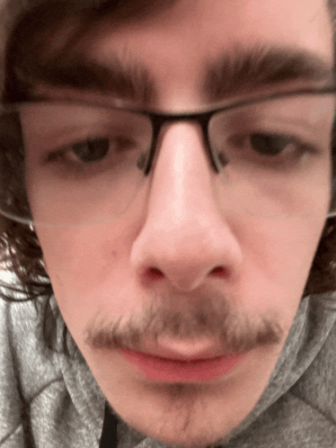 a close up of a man 's face with glasses on