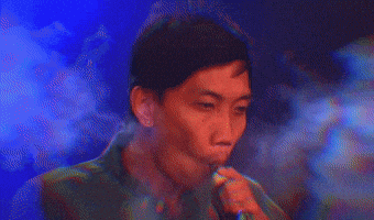 a blurry picture of a man blowing fire in a dark room