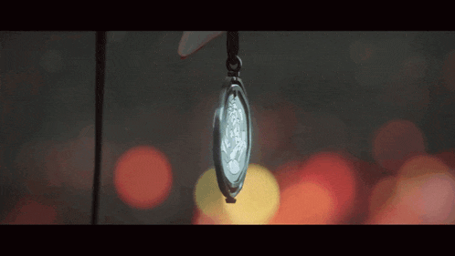 a close up of a watch hanging from a string with a blurry background