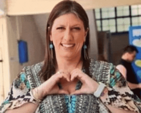 a woman is smiling and making a heart with her hands .