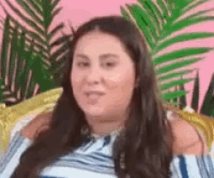 a woman is sitting on a couch with her arm around her shoulder and making a funny face .