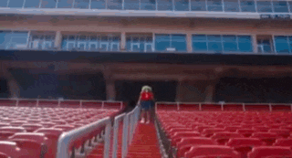 a woman is walking up stairs in an empty stadium .