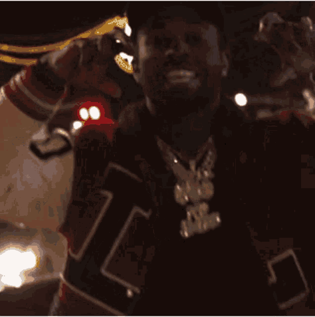 a man wearing a varsity jacket and a hat with the letter l on it