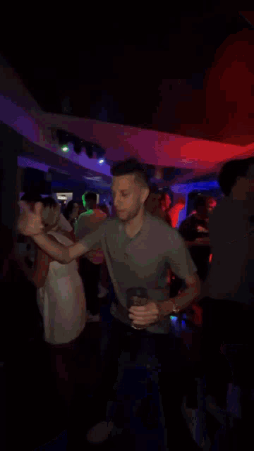 a man in a gray shirt is dancing in a crowded room