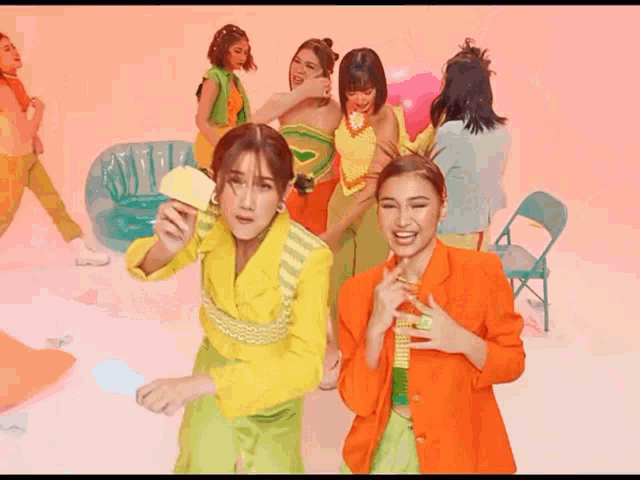 a group of women are standing in a room and one of them is holding an apple