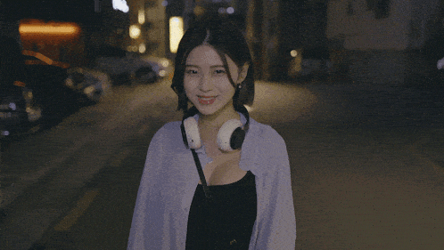a woman wearing headphones is walking down a street