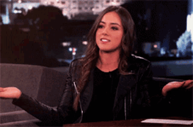 a woman in a leather jacket is sitting at a table