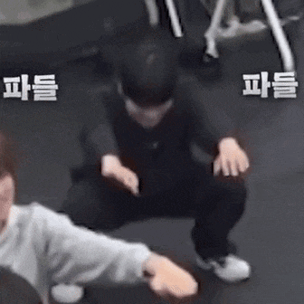 a man is squatting down in a gym while another man watches .