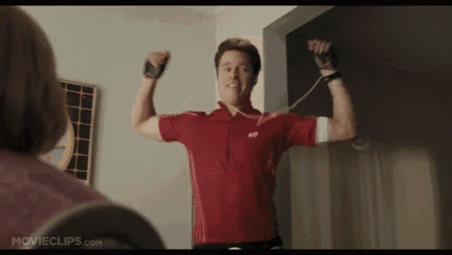 a man in a red shirt is flexing his muscles in front of a woman .
