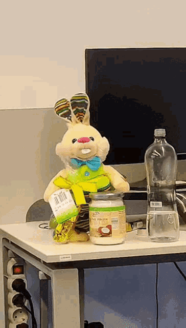 a stuffed bunny sits next to a jar of coconut oil