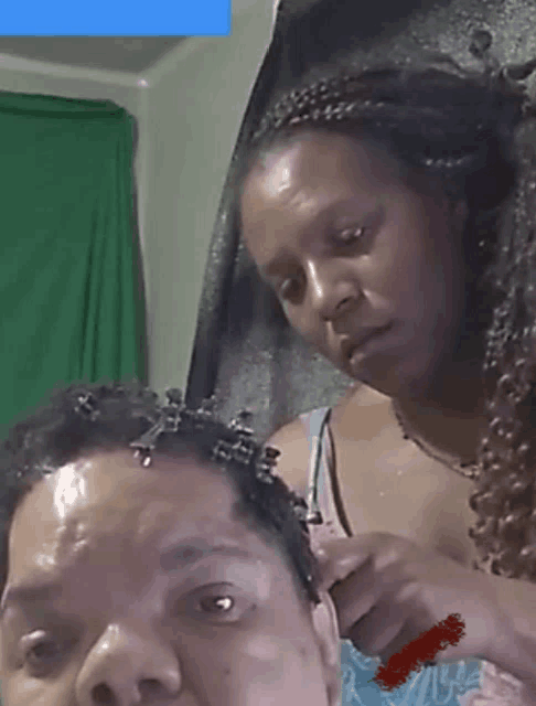 a woman braids a man 's hair while another woman watches
