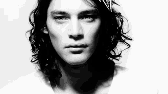 a black and white photo of a young man with long hair