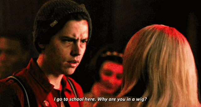 a man in a beanie talks to a woman who is wearing a wig