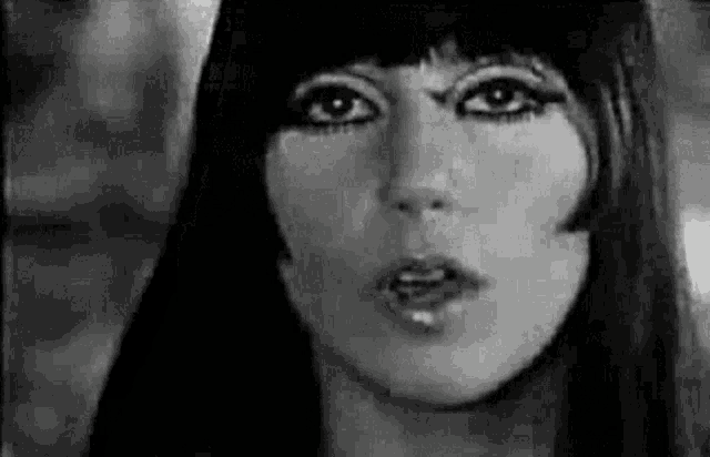 a black and white photo of a woman 's face with long hair and bangs .