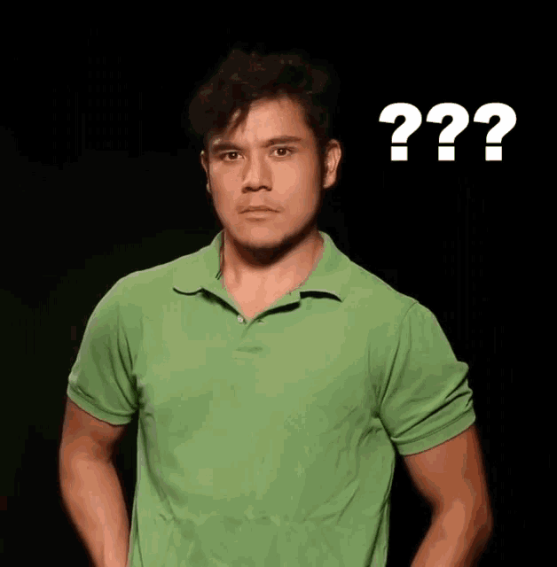 a man in a green shirt is making a surprised face in front of a sign that says " question mark "
