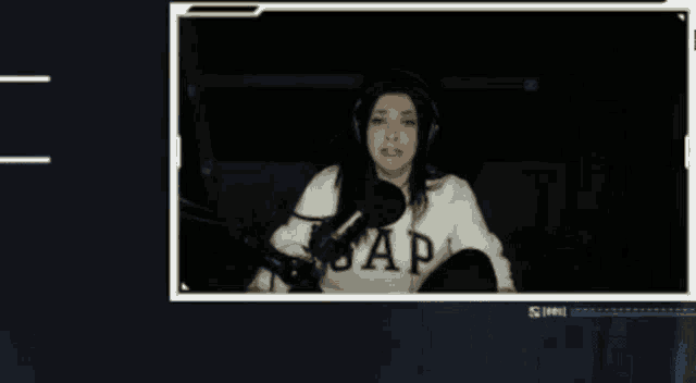 a woman wearing headphones and a gap sweater is sitting in front of a microphone