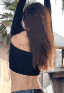 the back of a woman wearing a black crop top and black jeans
