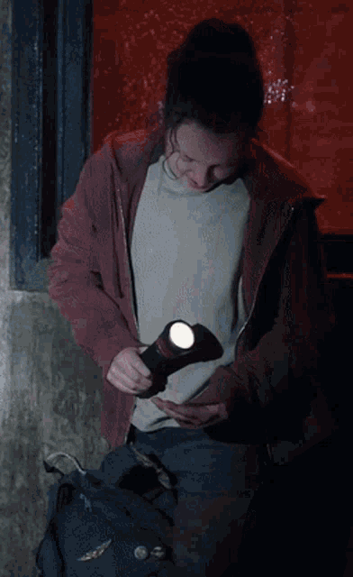 a woman in a red hoodie is holding a flashlight in her hand