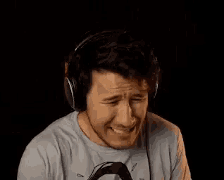 a man wearing headphones and a gray shirt is making a funny face .