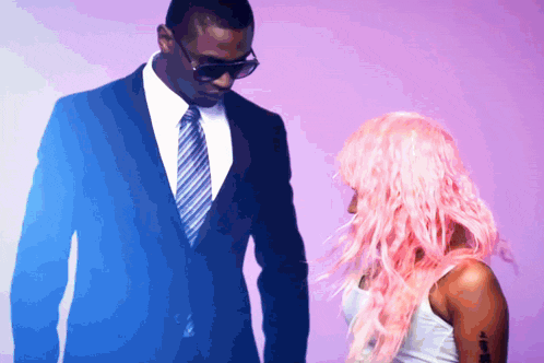 a man in a blue suit and tie stands next to a woman with pink hair
