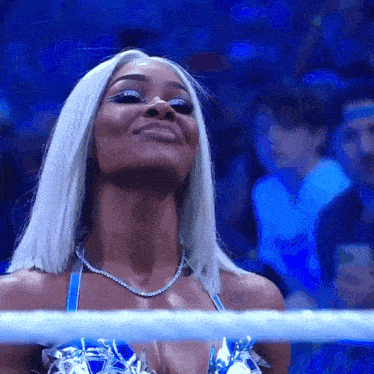a woman with white hair is standing in a wrestling ring looking up