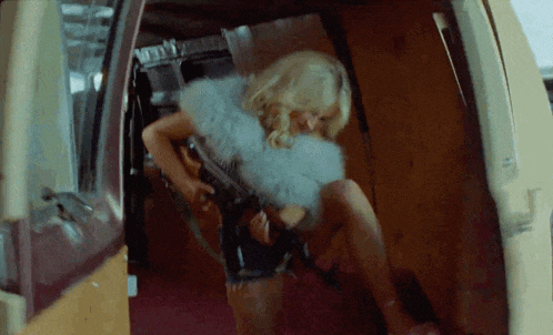 a woman is sitting in the back of a van with a gun .