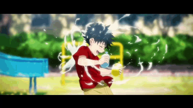 a boy in a red shirt is holding a bottle of water in a playground .