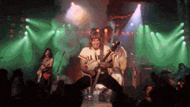 a man playing a guitar wearing a shirt that says ' aa ' on it