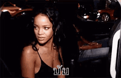 a woman in a black tank top is standing in a car .