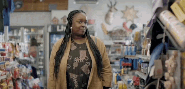 a woman in a brown jacket is standing in a store looking at something .