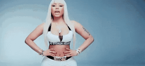 a woman is standing with her hands on her hips wearing a white top and white shorts .