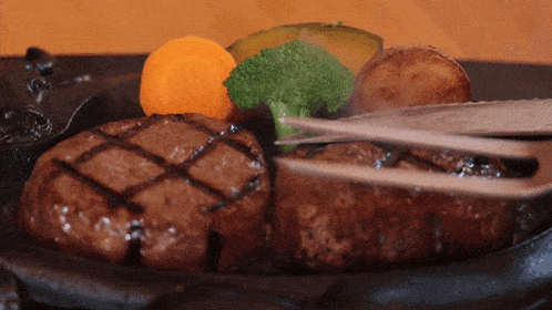 a close up of a steak with broccoli and carrots