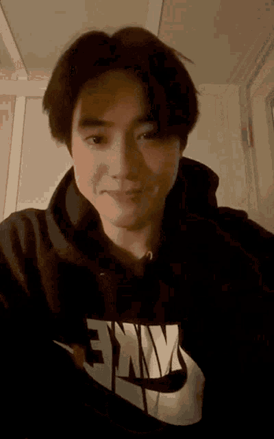 a young man wearing a black nike hoodie looks at the camera