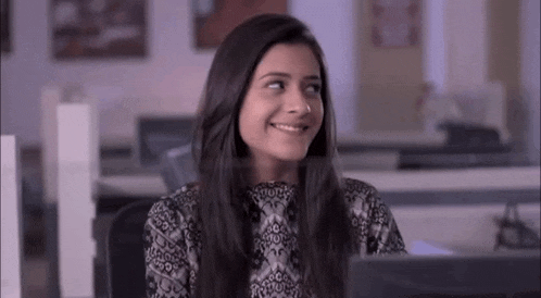 a woman is smiling while sitting at a desk in front of a computer .