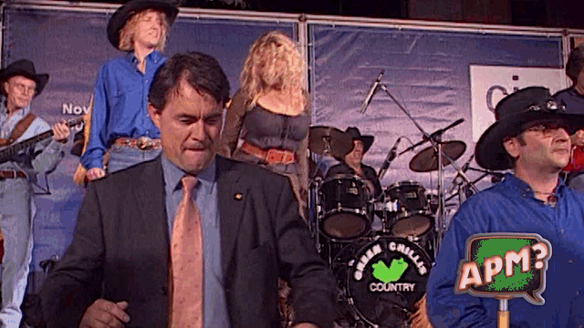 a man in a suit stands in front of a drum set that says green country on it