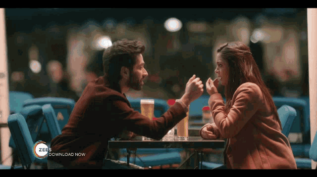 a man and a woman sitting at a table with a zeus download now advertisement